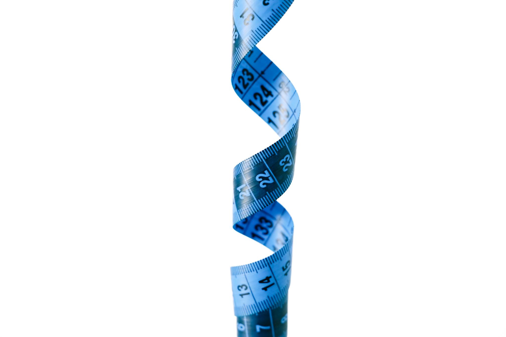 A spiraled blue measuring tape isolated against a white backdrop, symbolizing measurement and precision.